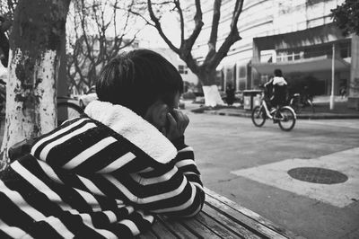Boy wearing striped warm clothing while leaning on table at street
