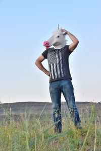 Man wearing horse costume while standing on field against sky