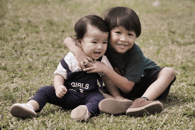 Portrait of mother and daughter sitting on field