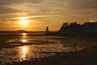 Lighthouse on beach at prince edward island against sky during sunset