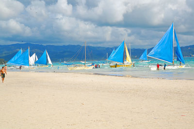 Sailboats on beach against sky