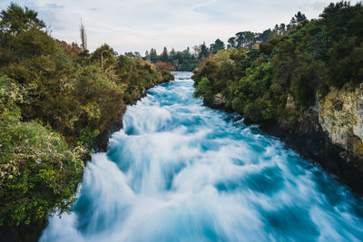 Scenic view of waterfall by sea against sky