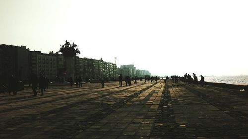 Silhouette of people in city against clear sky