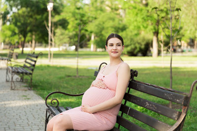 Portrait of woman sitting on bench in park