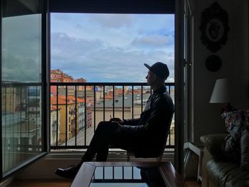 Thoughtful man sitting on chair by window at home