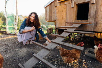 Joyful woman in chicken coop enjoying farm life by feeding chickens