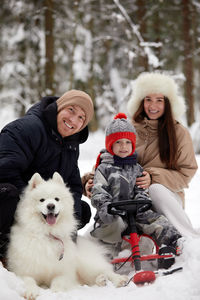 Portrait of young woman with dog on snow