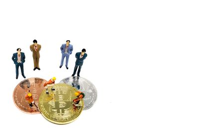 Bitcoins and figurines on white background