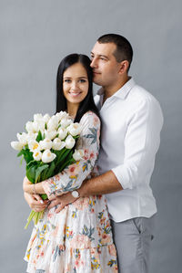 A couple in love with a bouquet of tulips in the studio on a gray background