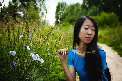 Close-up of young woman by flowering plants in forest