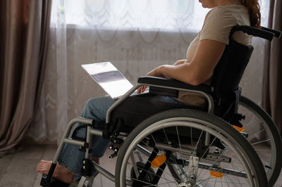 Midsection of woman using laptop sitting on wheelchair