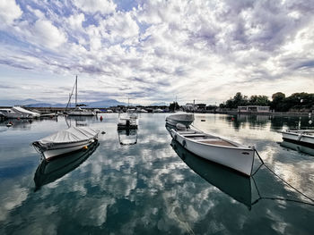 Sailboats moored on sea against sky