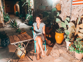 Portrait of young woman sitting on potted plant