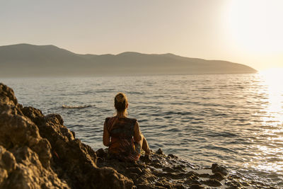 Rear view of woman standing at beach against clear sky