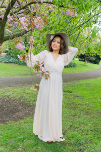 Young woman smiling while standing on grass in park