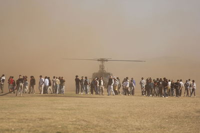 People by helicopter on land against sky