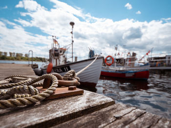 Fishing boats moored at harbor against sky