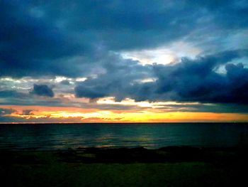 Scenic view of sea against dramatic sky during sunset