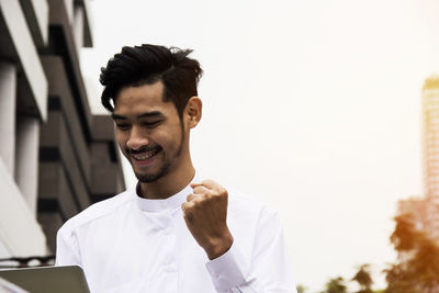 Smiling man clenching fist outdoors