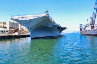 Ship moored in sea against clear blue sky