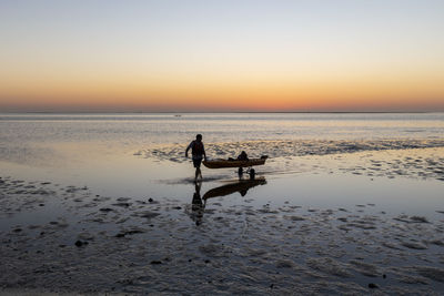 People on beach against sky during sunset