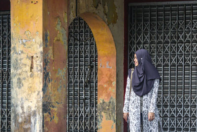 Woman wearing hijab standing at abandoned building