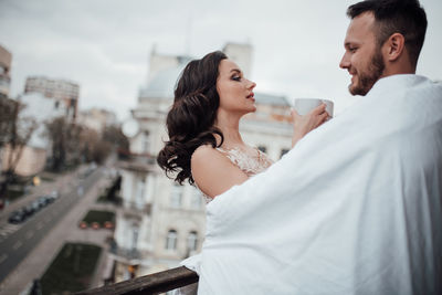 Couple holding coffee cup looking at cityscape