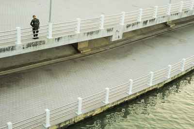 Man stands on the concrete walkway along the bank of the river