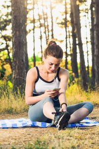 Young woman sitting on table against trees