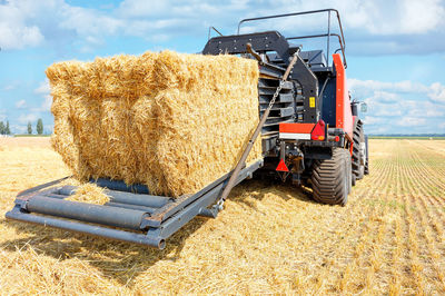 A modern agricultural machine collects straw into large bales after the end of the wheat harvest.