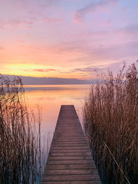 Pier over lake against sky during sunset