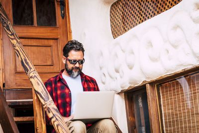 Man using laptop while sitting on steps