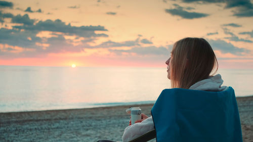 Rear view of woman at beach during sunset