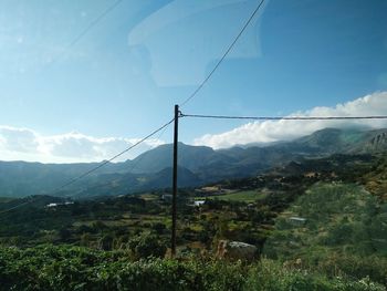 Overhead cable car over mountains against sky