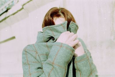 Close-up of woman wearing jacket against wall