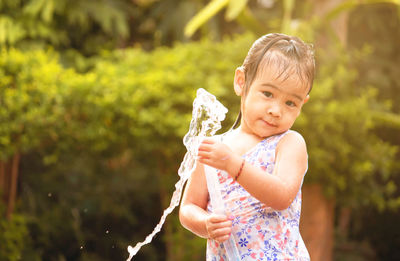 Portrait of cute girl holding garden house while standing in yard