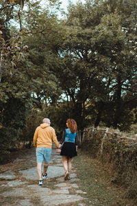 Rear view of women walking on footpath amidst trees