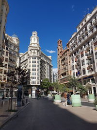 Street amidst buildings against blue sky