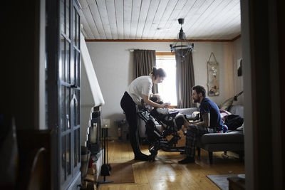 Parents taking care of disabled child in wheelchair at home