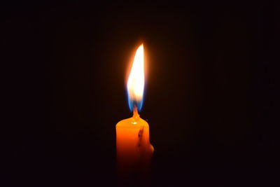 Close-up of lit candle in darkroom