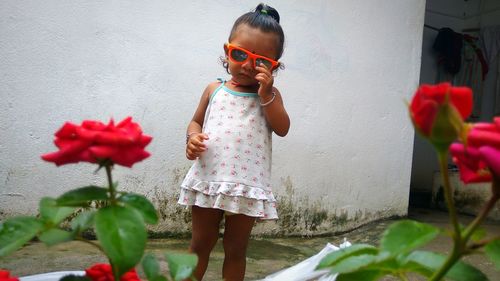 Full length of girl standing by red roses