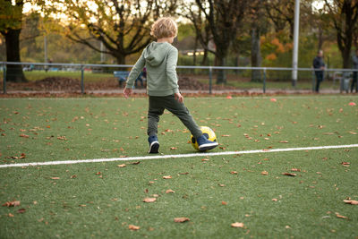 A little boy plays soccer with his father on the soccer field