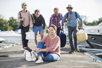 Group of playful friends looking at happy woman on pier at harbor