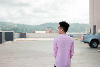 Young man standing in city against sky