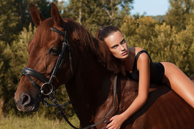 Portrait of beautiful woman riding brown horse on field