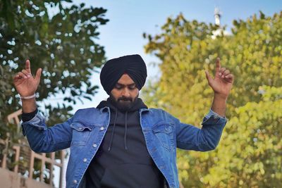 Young man wearing turban standing against trees