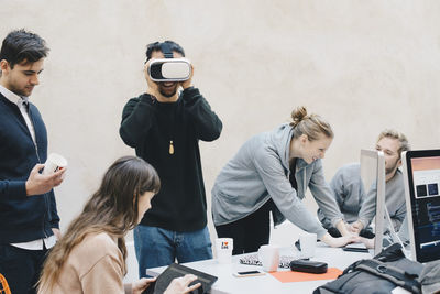 Male computer programmer using vr glasses while colleagues working in office