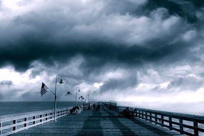 Pier on sea against cloudy sky