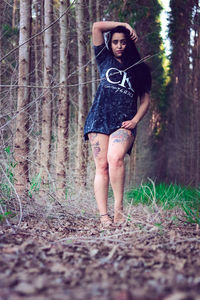 Full length portrait of young woman standing in forest