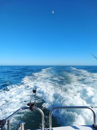 Man sailing on sea against clear blue sky